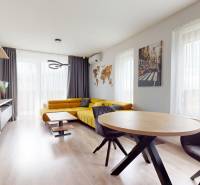 Wohnzimmer in einer 3-Zimmer-Wohnung mit Sofa, hellen Vorhängen und Holzboden.