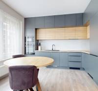 Eine Küche mit moderner Küchenzeile, rundem Tisch und einem Boden mit Holzdekor in einer 3-Zimmer-Wohnung.