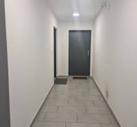 Der Innenraum des Flurs mit weißen Wänden und grauen Fliesen in einer 3-Zimmer-Wohnung.