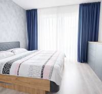 Schlafzimmer in einer 3-Zimmer-Wohnung mit Bett, blauen Vorhängen und Kommode.