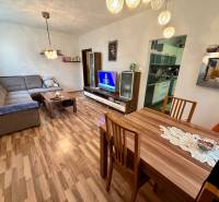 Wohnzimmer in einer 3-Zimmer-Wohnung mit Holzboden, Sofa und Fernseher.