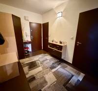 Eingangsbereich mit dunklen Türen, Kommode und Boden mit Holzdekor in einer 3-Zimmer-Wohnung.