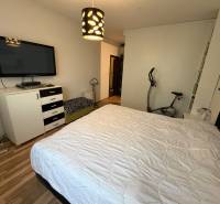 Schlafzimmer in einer 3-Zimmer-Wohnung mit Bett, Fernseher und Boden mit Holzdekor.