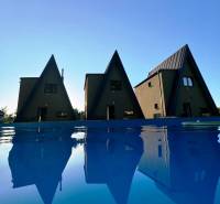 Häuser auf der Eva-Straße in Holčíkovce am Pool mit blauer Wasseroberfläche.