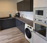 Küche in einer 3-Zimmer-Wohnung mit schwarzen Schränken und einem Boden in Holzoptik.