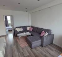 Wohnzimmer mit großem Sofa und Fernseher, in einer 3-Zimmer-Wohnung mit Holzboden-Dekor.