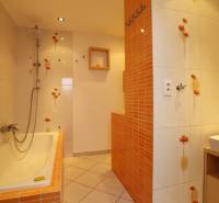 Badezimmer mit orangefarbenen Fliesen in einer 3-Zimmer-Wohnung, mit Waschbecken und Badewanne mit Kacheln.