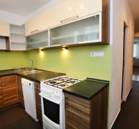 Küche in einer 3-Zimmer-Wohnung mit Holzboden und grüner Wandverkleidung.