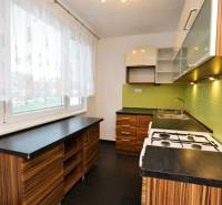 Küche in einer 3-Zimmer-Wohnung mit grünen Fliesen und einem Boden in Holzoptik.