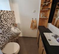 Badezimmer in einem Einfamilienhaus mit Waschbecken, Spiegel und Mosaikfliesen.