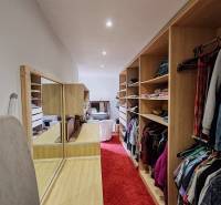 Ein Kleiderschrank in einem Einfamilienhaus mit rotem Teppich und eingebauten Regalen.
