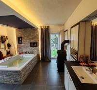 Geräumiges Badezimmer mit Badewanne und Fliesen in einem Einfamilienhaus, Boden mit Holzdekor.