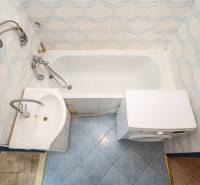 Badezimmer in einer 2-Zimmer-Wohnung mit Badewanne, Waschbecken und Waschmaschine, gefliest.