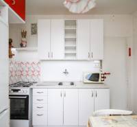 Küche in einer 2-Zimmer-Wohnung mit weißen Schränken, Herd und Mikrowelle.