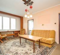 Wohnzimmer mit Sofa, Sesseln und Tisch in einer Zweizimmerwohnung.