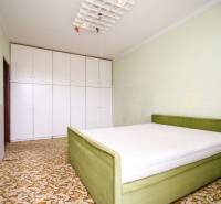 Schlafzimmer in einer 2-Zimmer-Wohnung mit Bett und Kleiderschrank auf einem gemusterten Teppich.