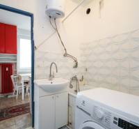 Badezimmer in einer 2-Zimmer-Wohnung mit Waschmaschine, Waschbecken und Fliesen.