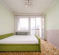 Schlafzimmer in einer 2-Zimmer-Wohnung mit Bett, Tapeten und Zugang zum Balkon.