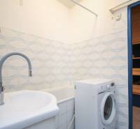 Badezimmer mit Waschbecken, Waschmaschine und Badewanne in einer 2-Zimmer-Wohnung.