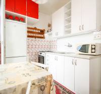 Küche in einer 2-Zimmer-Wohnung mit eingebauten Geräten und Esstisch.