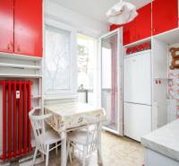 Küche in einer 2-Zimmer-Wohnung mit gelbem Boden, roten Schränken und einem Tisch mit weißen Stühlen.