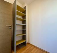 Ein Holzregal mit Regalböden in einem Raum mit einem Boden in Holzoptik, 4-Zimmer-Wohnung.
