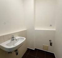 Toilette in einer 4-Zimmer-Wohnung mit weißem Waschbecken und schwarzen Fliesen.