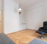 Innenraum einer 4-Zimmer-Wohnung mit Sessel, weißer Kommode und Boden in Holzoptik.