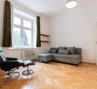 Helles Wohnzimmer mit Holzboden in einer 4-Zimmer-Wohnung, graues Sofa, Sessel.