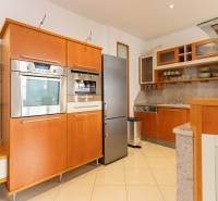 Küche in einer 4-Zimmer-Wohnung mit Edelstahlgeräten und Holzschränken.