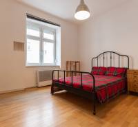 Schlafzimmer in einer 4-Zimmer-Wohnung mit Bett, Nachttischen und Boden mit Holzdekor.
