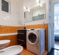 Badezimmer mit eingebauter Waschmaschine und orangefarbenen Fliesen in einer 4-Zimmer-Wohnung.