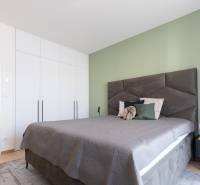 Schlafzimmer mit Bett, hellen Einbauschränken und Nachttisch in einer 2-Zimmer-Wohnung.