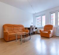 Wohnzimmer mit orangefarbenem Sofa und Holzboden in einer Zweizimmerwohnung.