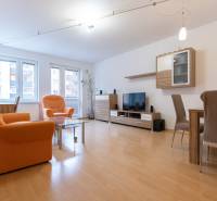 Wohnzimmer in einer Zweizimmerwohnung mit orangefarbenen Sesseln und einem Boden in Holzoptik.
