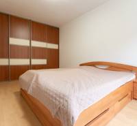 Schlafzimmer mit Holzboden und Einbauschrank in einer Zweizimmerwohnung.
