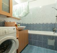 Badezimmer in einer 2-Zimmer-Wohnung mit Waschmaschine, Badewanne und blauen Fliesen.