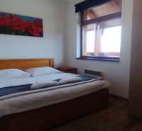 Schlafzimmer mit Doppelbett, Blumenbild und Schrank in einer 2-Zimmer-Wohnung.