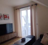 Wohnzimmer in einer 2-Zimmer-Wohnung mit Holzboden, Dekoration und Fernseher.