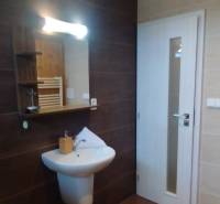 Badezimmer in einer 2-Zimmer-Wohnung mit Waschbecken, Spiegel und hellen Fliesen.