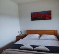 Schlafzimmer mit Doppelbett und Nachttischen aus Holz in einer Zweizimmerwohnung.
