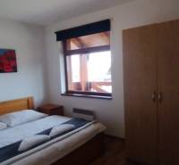 Schlafzimmer mit Doppelbett, Holzboden und Kleiderschrank in einer 2-Zimmer-Wohnung.