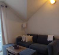 Wohnzimmer in einer Zweizimmerwohnung mit Sofa, Couchtisch und verglasten Balkontüren.