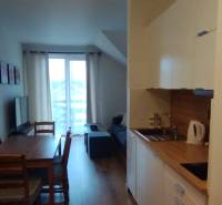 Küchenzeile und Esstisch mit Stühlen, 2-Zimmer-Wohnung, Boden mit Holzdekor.