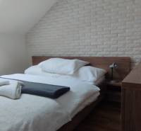 Schlafzimmer in einer 2-Zimmer-Wohnung mit Bett, Lampe und Ziegelverkleidung an der Wand.