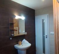 Badezimmer in einer 2-Zimmer-Wohnung mit dunklen Fliesen, Spiegel und weißem Waschtischunterschrank.
