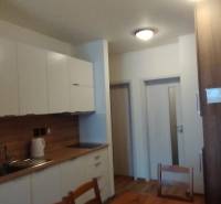 Küche in einer 2-Zimmer-Wohnung mit Holzboden und weißen Schränken.