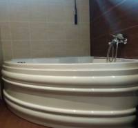Badezimmer mit Eckbadewanne, Dusche und Regalschrank in einer 2-Zimmer-Wohnung.