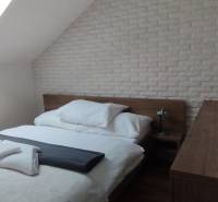 Schlafzimmer mit Bett und Dachfenster in einer 2-Zimmer-Wohnung mit dekorativem Ziegelverkleidung.