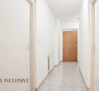 Flur mit weißen Wänden, Fliesenboden und Holztüren in einer Zweizimmerwohnung.